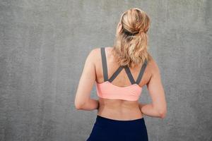 Sportive girl near the wall in headphones view from the back photo