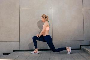 Young girl near a gray wall stretches muscles photo