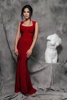 girl in a red evening dress on a gray background photo