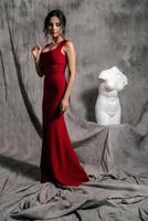 girl in a red evening dress on a gray background photo