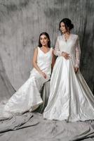 Two girls in a wedding dress studio portrait on a gray background photo
