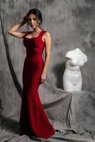 girl in a red evening dress on a gray background photo