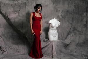 girl in a red evening dress on a gray background photo