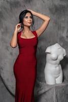 girl in a red evening dress on a gray background photo