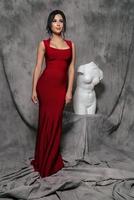 girl in a red evening dress on a gray background photo