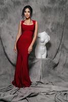 girl in a red evening dress on a gray background photo