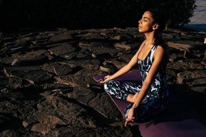 Girl meditates in nature sits with closed eyes on stones photo