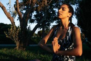 un niña es comprometido en yoga en naturaleza en un filote estera cerrado ojos foto