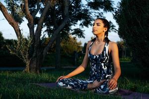 A girl is engaged in yoga in nature on a phylote mat meditates at sunset photo