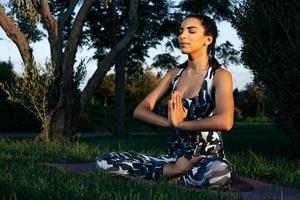 A girl is engaged in yoga in nature on a phylote mat closed eyes photo
