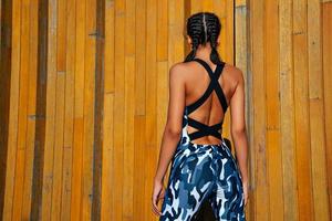 sports girl on a wooden wall background with his back to the frame medium shot don't look into the frame photo