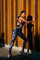 sports girl on a wooden wall background vertical composition with his hands on the wall photo