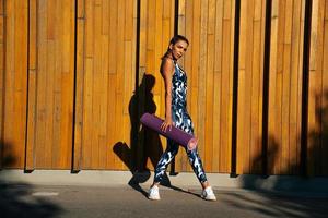 sports girl on a wooden wall background with mats in hand full-length portrait photo