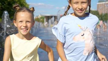 Little adorable girls have fun in street fountain at hot sunny day video