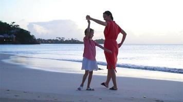 la joven y hermosa madre y su adorable hijita se divierten en la playa tropical video