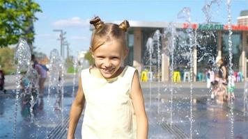 Little adorable girl have fun in street fountain at hot sunny day video