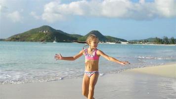 pequeño activo niña haciendo volteretas en blanco playa. video