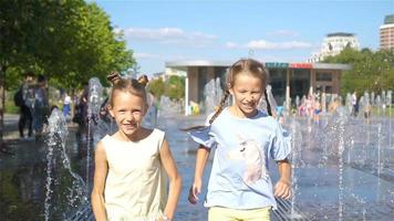 Little adorable girls have fun in street fountain at hot sunny day video