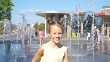 poco adorabile ragazza avere divertimento nel strada Fontana a caldo soleggiato giorno video