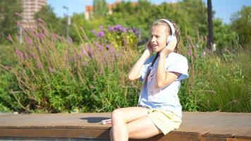 menina adorável ouvindo música no parque video