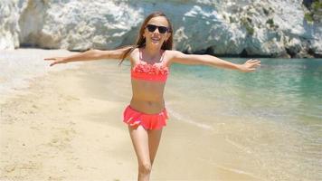 Active little girl at beach having a lot of fun. Cute kid making sporty exercises on the seashore video