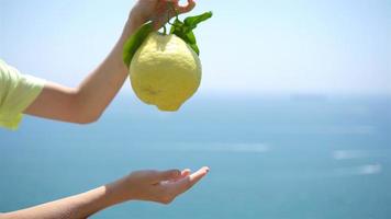 groot geel citroen in hand- in achtergrond van middellandse Zee zee en lucht. video