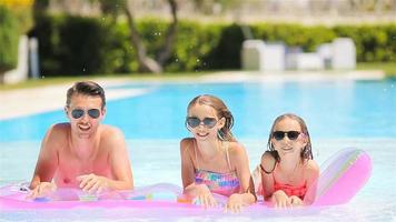 Father and two kids enjoying summer vacation in luxury swimming pool