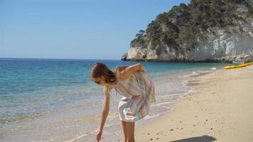 schönes kleines Mädchen im Kleid am Strand, das Spaß hat. lustiges mädchen genießt sommerferien. video