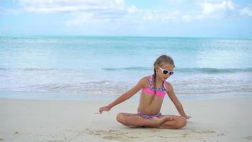 förtjusande liten flicka liggande på vit sandig strand video