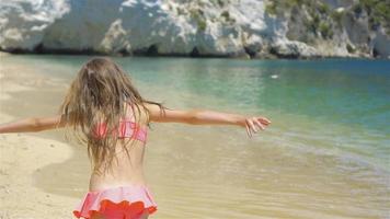 niña activa en la playa divirtiéndose mucho. lindo niño haciendo ejercicios deportivos en la orilla del mar video