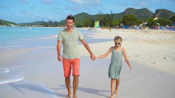 pai feliz e sua adorável filhinha na praia tropical caminhando juntos video