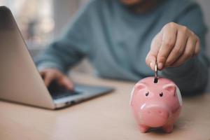 Budget and Saving money concept for financial accounting,Woman hand putting coin in piggy bank, financial plan and Money saving ideas, business finance and investment, life and family planning. photo
