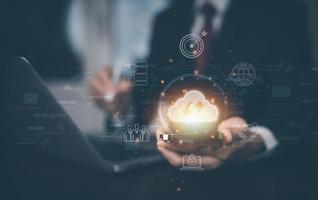 Businessman hand holding smartphone and laptop with cloud computing diagram show on hand. Cloud technology. Data storage. Networking and internet service concept, Cloud sharing download and upload photo