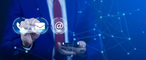 Communication and Contact us or Customer support hotline people connect. Hand using a laptop and touching on virtual screen contact icons, email and address, live chat with internet wifi. photo