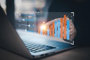 el tipo de mano del hombre de negocios en la computadora portátil de las ganancias de la empresa con los colegas, el socio, explica con el panel de control virtual, el gráfico de estadísticas, la infografía de acciones, los gráficos, la criptomoneda y las nuevas plataformas comerciales foto