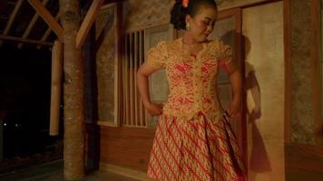 A Javanese woman with a traditional orange dress walks to the stage before the show begins video