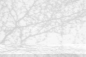 White Marble Table with Beautiful Tree Branches Shadow on Concrete Wall Texture Background, Suitable for Product Presentation Backdrop, Display, and Mock up. photo