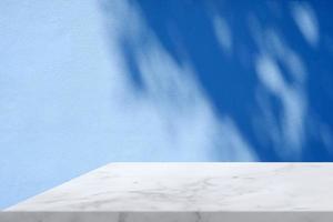 White Marble Table Corner with Light Beam, Shadow, and Spotlight on the Blue Concrete Wall Background, Suitable for Product Presentation Backdrop, Display, and Mock up. photo