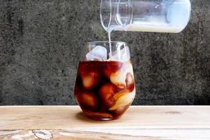 Cold Brew Black Coffee with Pouring Fresh Milk. photo