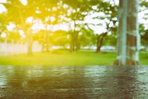 Close up Black Wooden Table with Blurred Garden and Light Leak Background. photo