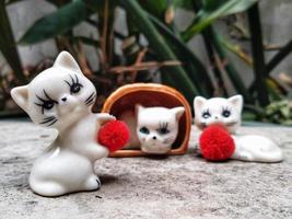 Neko figurine, ceramic cats sculpture place on outdoor with abstract background photo