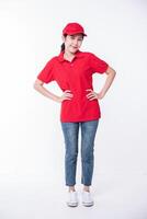 Image of  young delivery man in red cap blank t-shirt uniform standing on light gray background studio photo