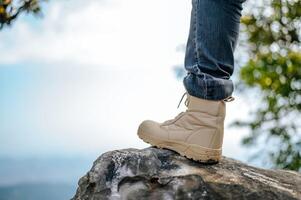 Leg in jeans wearing trekking sneakers on the mountain photo