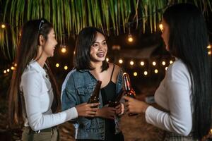 Portrait of Happy Asian friends having dinner party together - Young people toasting beer glasses dinner outdoor  - People, food, drink lifestyle, new year celebration concept. photo