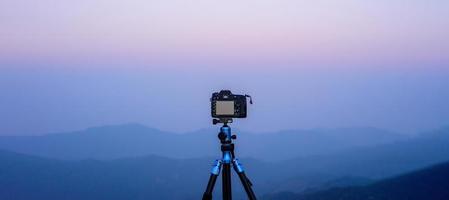 Camera on tripod Photographers take scenic views with mountain background photo
