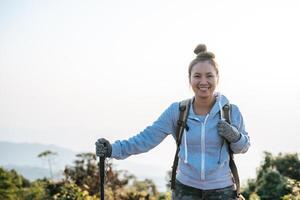 retrato de contento asiático caminante mujer con mochila mirando a cámara en montaña con Copiar espacio foto