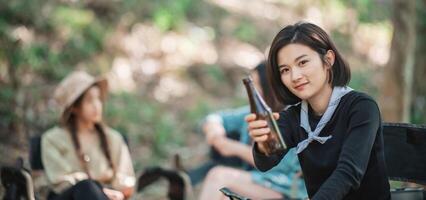 Young women cheer and drink beverage  front of camping tent photo