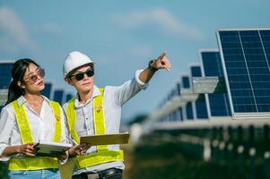 Asian Young Inspector Engineer man and female walking checking operation in solar farm photo