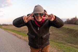 middle aged man wearing winter clothes have fun and making victory sign with hands outdoors photo