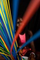 portrait of young pretty african teenager stands behind long colored straws photo